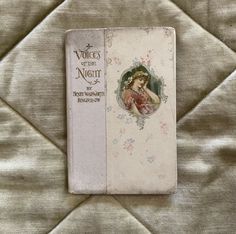 an old book is laying on a bed with the cover pulled back to reveal it's design