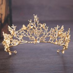 a gold tiara with flowers and leaves on it, sitting on a wooden table