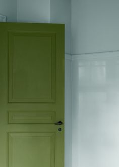 a green door in the corner of a room with white walls and carpet on the floor