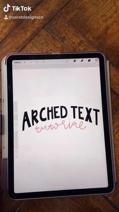 an ipad with the text'arched text imagine'written on it, sitting on top of a wooden table