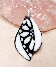 a black and white glass pendant sitting on top of a rock