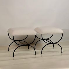 two black and white foot stools sitting on top of each other in front of a wall