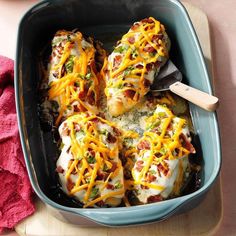 a casserole dish with cheese and other toppings in it on a cutting board