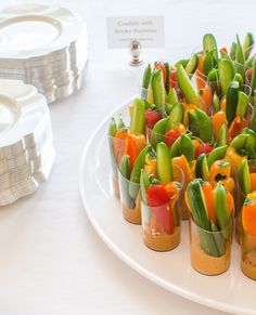 a white plate topped with lots of veggies on top of a table next to stacks of coins