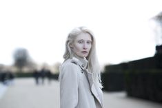 a woman with blonde hair is standing on the sidewalk