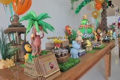 a table topped with lots of cake and balloons in the shape of animals on top of it