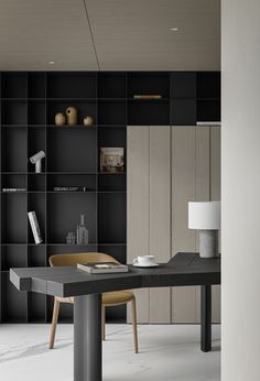 a black and white room with a table, chair, bookshelf and lamp