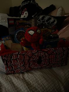 a spiderman themed gift bag sitting on top of a bed next to a teddy bear