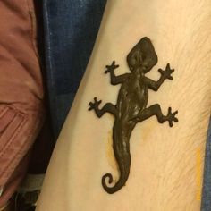 a small lizard tattoo on the arm