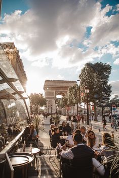 people are sitting at tables in front of the arc de trioe, paris's triumph