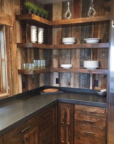 a kitchen with wooden cabinets and black counter tops, along with white dishes on the shelves