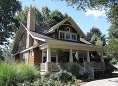 a small house with porches and windows on the front lawn, surrounded by trees