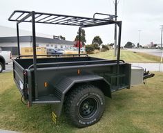 a black utility trailer parked in the grass