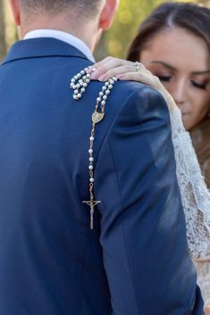 a bride and groom holding each other while wearing rosary necklaces with cross on it