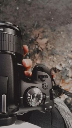 a person holding a camera in their right hand and looking at the camera with both hands