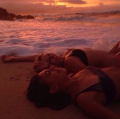 two women laying on the beach at sunset