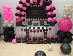 some black and pink balloons are in front of a stage set up for a party