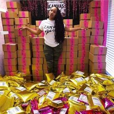 a woman standing in front of boxes with gold foil wrapped around her and arms outstretched