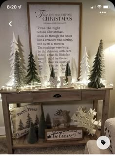 a table with christmas trees and lights on it in front of a sign that reads, the night before christmas