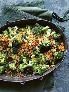 a skillet filled with broccoli and rice on top of a green towel