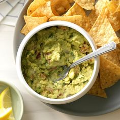 a bowl of guacamole with tortilla chips on the side