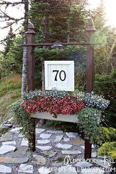 a sign that reads 70 on it in front of some trees and bushes with flowers