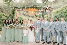 a group of people standing next to each other in front of a wooden structure with greenery