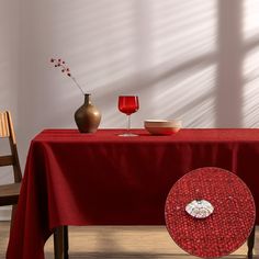 a table with a red cloth on it next to a vase and two empty glasses