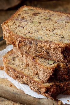 three slices of banana bread stacked on top of each other next to a wooden cutting board