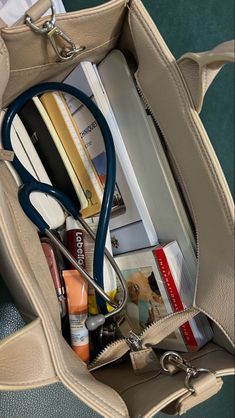 a doctor's stethoscope is in the pocket of a purse filled with medical supplies