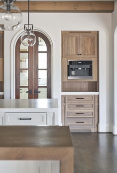 a kitchen with wooden cabinets and white counter tops next to an open door that leads to another room