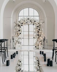 a wedding arch with flowers and candles in front of a large glass door that leads to an arched doorway