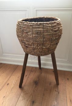 a large woven basket sitting on top of a wooden table next to a white wall