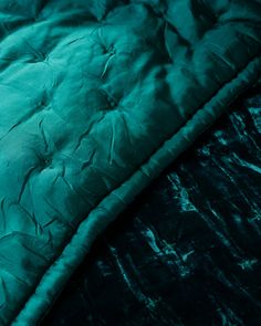 a close up view of a green comforter on a bed with blue sheets and pillows