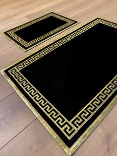 two black and gold rugs sitting on top of a wooden floor