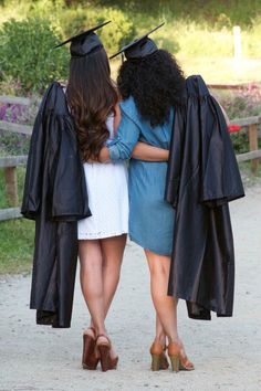 two women in graduation gowns hugging each other with their arms around one another and wearing black caps and gowns