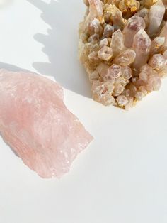 two pink crystals sitting next to each other on a white surface