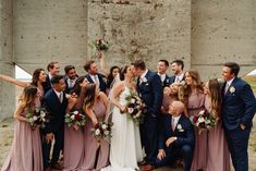 a group of people standing next to each other in front of a cement wall with flowers