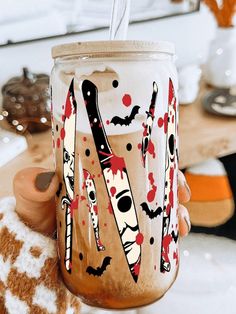 a person holding a jar with scissors painted on it and a straw in the cup