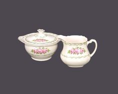 two white dishes with pink flowers and leaves on them, one has a creamer and the other is a sugar bowl