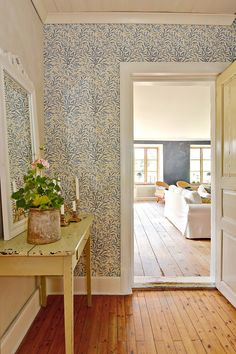 an open door leading to a living room with blue wallpaper and wood flooring