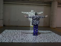 a person standing in front of a screen with words projected on the wall behind them