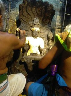 two men are working on an ancient statue