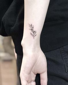 a woman's hand with a small flower tattoo on the left side of her wrist