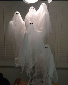 three white ghost decorations hanging from a ceiling