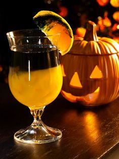 a glass filled with liquid sitting on top of a table next to a jack - o'lantern