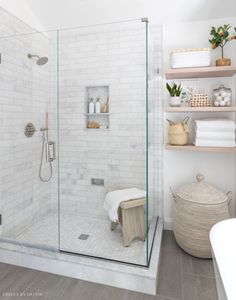 a bathroom with a walk in shower next to a bathtub and shelves filled with towels