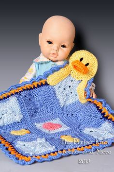 a baby is holding a crocheted blanket with a yellow duck on it's back