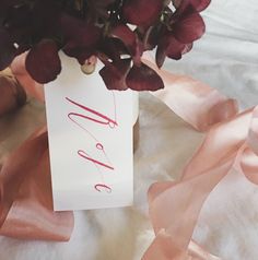 a vase filled with purple flowers sitting on top of a white table covered in pink ribbon