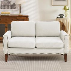 a white couch sitting in a living room next to a table and lamp on top of a rug